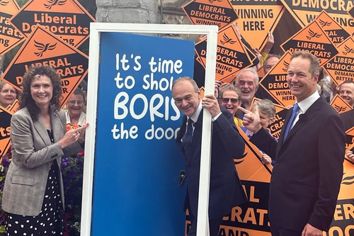 Lib Dem leader Ed Davey posing with a blue door to send a message to Boris Johnson